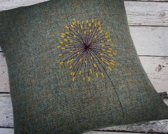 May include: A green and blue tweed pillow with an embroidered yellow dandelion design.