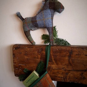 May include: A plaid stocking with a green ribbon hanging from a wooden mantel. A small book titled "The Observer's Book of Trees" is inside the stocking. A plaid horse figurine is perched on the mantel above the stocking.
