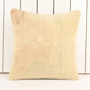 May include: A beige throw pillow with a woven texture. The pillow is made of a soft, natural fabric and has a subtle pattern.