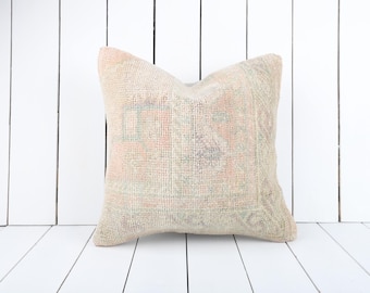 Puede incluir: Una almohada de color beige claro con un patrón floral descolorido. La almohada está hecha de una tela suave y tejida y tiene un aspecto vintage sutil.