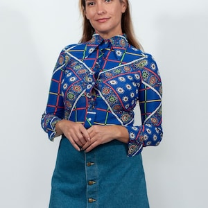 Könnte beinhalten: Eine Frau trägt ein langärmliges Hemd mit blau-weißem Muster, einen Jeans-Minirock und braune Stiefel bis zum Knie.