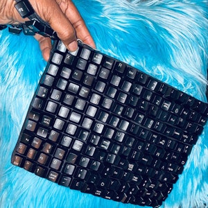May include: A black keyboard with a blue and white fuzzy background. The keyboard has all the standard keys, including function keys, arrow keys, and number keys.