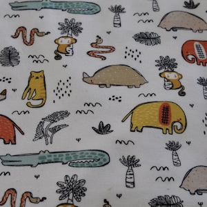 Può includere: Tessuto bianco con un motivo ripetuto di vari animali, tra cui elefanti, armadilli, serpenti, coccodrilli e scimmie. Gli animali sono illustrati in uno stile cartone animato con colori vivaci.