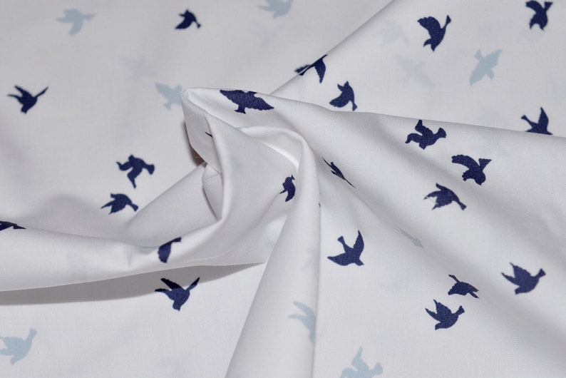 May include: White fabric with a repeating pattern of dark blue flying birds.