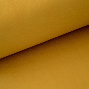 May include: Close-up of a folded piece of fabric in a rich mustard yellow color. The fabric has a subtle texture and a smooth, even surface.