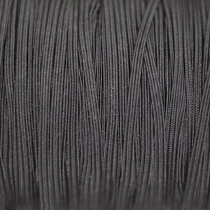 May include: Close-up of a spool of black elastic cord. The cord is tightly wound and has a smooth, matte finish.