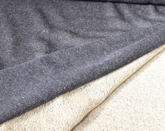 Op de afbeelding: Een close-up van twee stofstalen. Eén is een donkerblauwe, textuurrijke stof, de andere is een lichtbeige, textuurrijke stof.