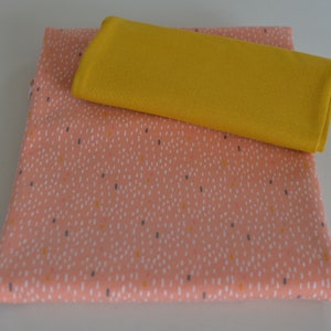 May include: Two pieces of fabric, one is a peach colored fabric with a white and yellow speckled pattern, the other is a solid yellow fabric.
