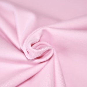 May include: Close-up of a soft, pink fabric with a smooth texture. The fabric is folded and draped, creating a gentle, flowing effect.