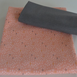 May include: Two pieces of fabric, one pink with a white and yellow speckled pattern and one gray.