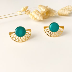 Op de afbeelding: Een paar gouden oorbellen met een teal groene ronde steen in het midden van elke oorbel. De oorbellen zijn halfrond met een geometrisch ontwerp.