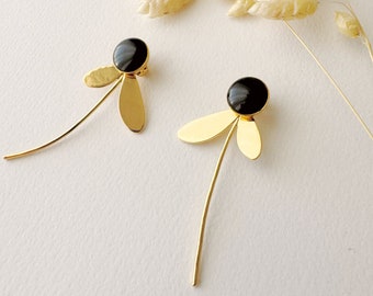 May include: A pair of gold earrings with black stone accents. Each earring features a delicate stem with three gold leaves and a round black stone.