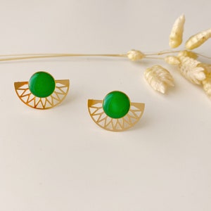 Peut inclure: Une paire de boucles d'oreilles en or avec une pierre verte au centre de chaque boucle d'oreille. Les boucles d'oreilles sont en forme de demi-cercle avec un motif géométrique.