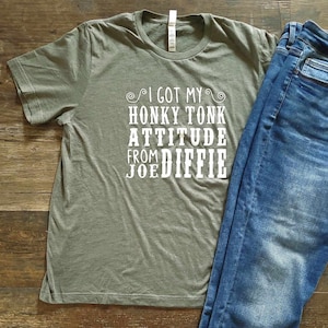 May include: A green t-shirt with white text that reads "I got my Honky Tonk Attitude from Joe Diffie".