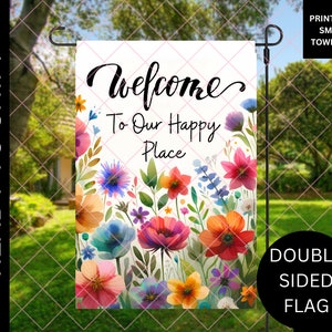 May include: A double-sided garden flag with the words "Welcome To Our Happy Place" surrounded by watercolor flowers in shades of pink, orange, blue, and purple. The flag is ready to ship and printed in Small Town USA.