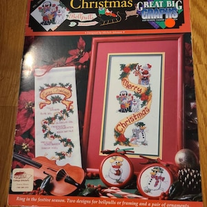 May include: A Christmas-themed craft pattern book featuring cross-stitch designs. The cover displays a framed "Merry Christmas" design, bellpulls, and snowman ornaments. The book includes the text "Great Big Graphs" and "Bellpulls & ornaments".