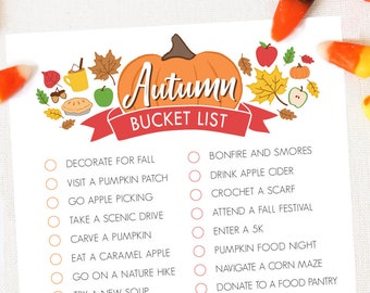 Puede incluir: Un papel blanco con una ilustración de calabaza naranja y las palabras "Autumn Bucket List" en negro y naranja. La lista incluye actividades de otoño como visitar un huerto de calabazas y hornear un pastel. Caramelos de maíz están esparcidos.