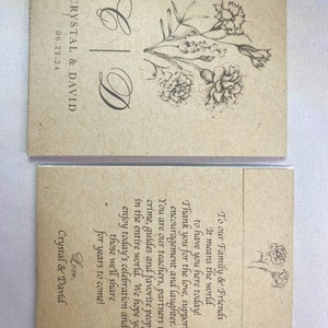 May include: A simple, rustic wedding announcement card with a floral design and the text "Crystal & David" and "06.22.24". The card is printed on brown paper with a textured surface.