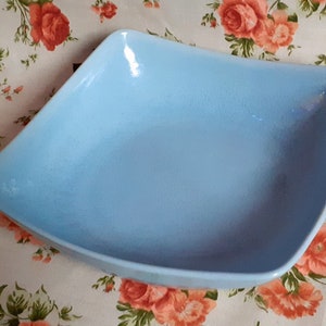May include: A light blue square ceramic serving bowl. The bowl is empty and has a slightly textured surface.
