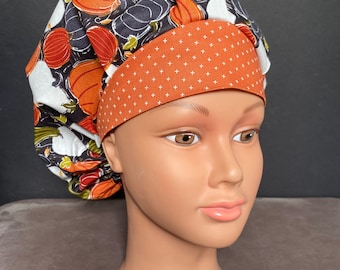 May include: A brown and white patterned scrub hat with a solid orange band. The hat has a pumpkin and leaf design.