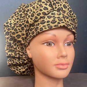 May include: A brown and gold leopard print surgical cap with a gathered top.