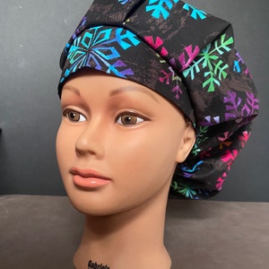 May include: A black scrub hat with a colorful snowflake pattern. The hat is made of soft, comfortable fabric and is perfect for nurses, doctors, and other healthcare professionals.