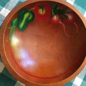 May include: A wooden bowl with a red rim and hand-painted vegetables. The vegetables include a red tomato, green leaves, and two red radishes.