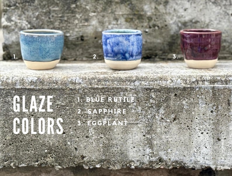 K&ouml;nnte beinhalten: Drei kleine Keramikbecher mit einer glatten, unglasierten beigen Basis und gl&auml;nzenden oberen Abschnitten in den Farben Blaurutil, Saphir und Aubergine. Der Text GLAZE COLORS steht links, mit den Nummern 1, 2 und 3 f&uuml;r die jeweiligen Farben.