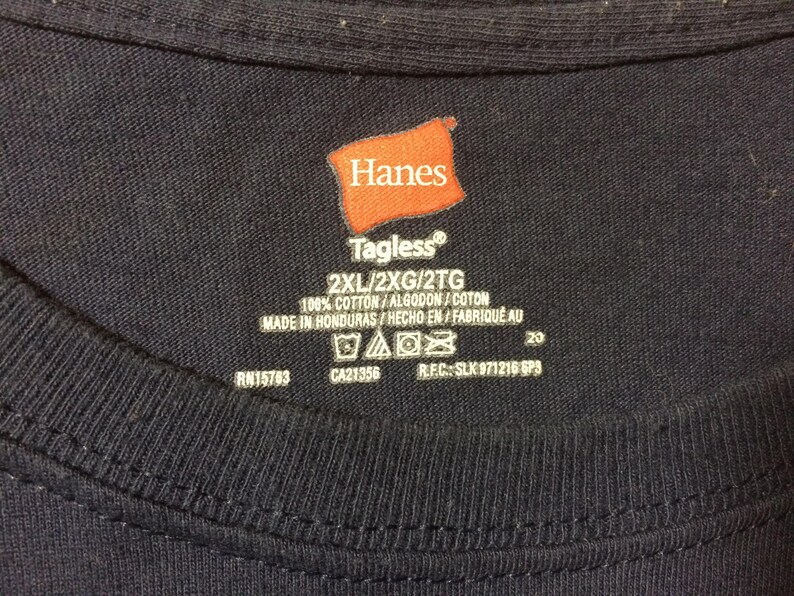 May include: A navy blue t-shirt with a Hanes Tagless&reg; label. The label indicates the shirt is size 2XL and is made of 100% cotton. The shirt is made in Honduras.