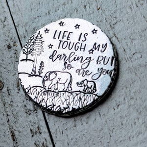 May include: Silver charm with a black and white illustration of a forest scene with two elephants and the text "Life is tough my darling but so are you".