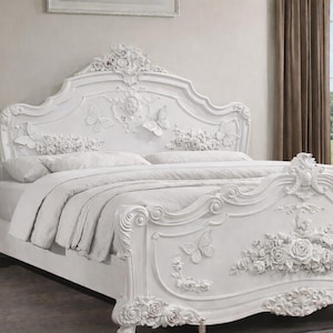 May include: White ornate bed frame with floral and butterfly carvings. The headboard and footboard feature detailed relief designs. The bed is part of a bedroom furniture set, including a matching nightstand.