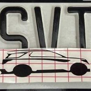 May include: A black decal featuring the letters SVT in a bold, sans-serif font positioned above a black line-art silhouette of an SUV. The vehicle graphic is overlaid with a red grid pattern on a white backing, designed for automotive application.