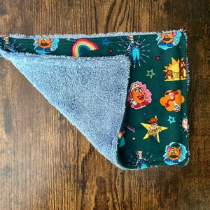 May include: A blue and green dishcloth with a Toy Story theme. The dishcloth features characters like Woody, Buzz Lightyear, and Mr. and Mrs. Potato Head.