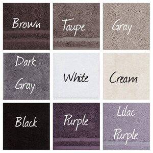 May include: Nine different colored towels, each with a word describing the color written on it. The colors are brown, taupe, gray, dark gray, white, cream, black, purple, and lilac purple.