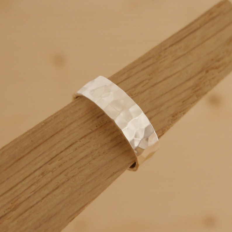 May include: A silver hammered band ring. The ring is thick and has a textured surface.