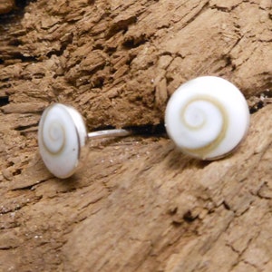May include: A pair of silver stud earrings with white and brown shell inlays. The shell inlays have a spiral pattern.