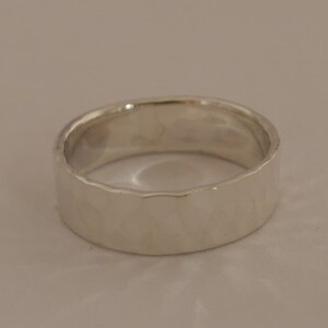 May include: A silver band ring with a hammered texture.