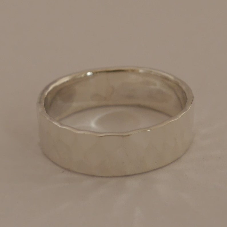 May include: A silver band ring with a hammered texture.