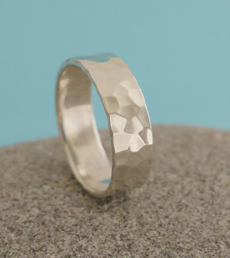 May include: A silver hammered band ring. The ring is wide and has a textured surface.