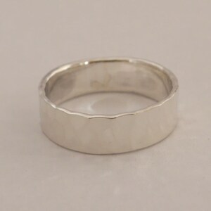 May include: A silver hammered band ring with a smooth, polished finish.