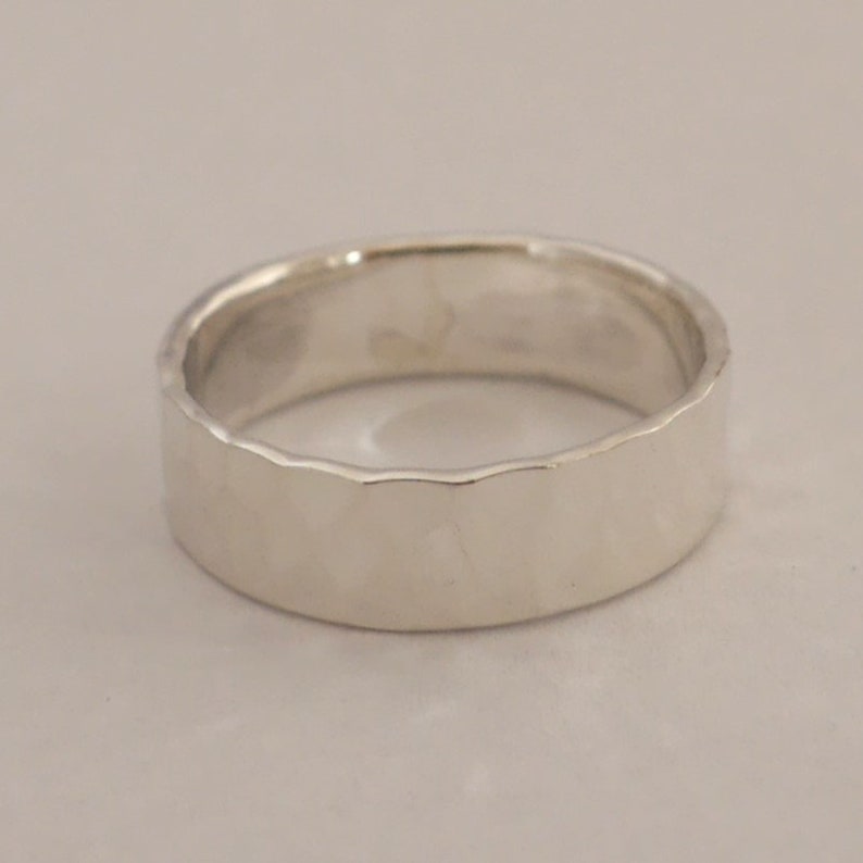 May include: A silver hammered band ring with a smooth, polished finish.