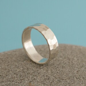 May include: A silver hammered band ring. The ring is smooth on the inside and has a textured hammered finish on the outside.