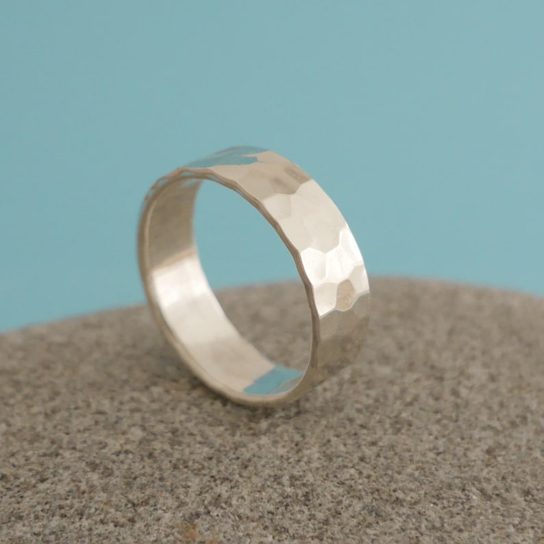 May include: A silver hammered band ring. The ring is smooth on the inside and has a textured hammered finish on the outside.