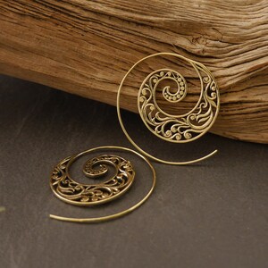 May include: A pair of gold-toned spiral earrings with a delicate floral design. The earrings are made of metal and have a wire-like structure.