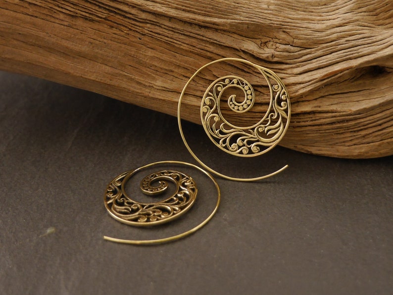 May include: A pair of gold-toned spiral earrings with a delicate floral design. The earrings are made of metal and have a wire-like structure.