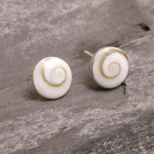 May include: A pair of silver stud earrings with white shell inlays featuring a spiral pattern.