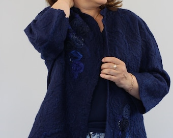 May include: A navy blue jacket with a textured finish and floral detailing. The open jacket reveals a dark blue top and blue jeans. The floral embellishments are in various shades of blue. The jacket has a collarless design.