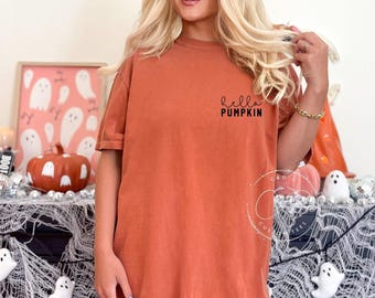 May include: A burnt orange t-shirt with the text "hello pumpkin" in black on the front.