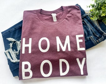 May include: A maroon t-shirt with the text "HOME BODY" printed in white.