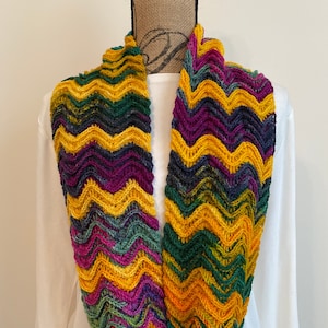 May include: A colorful crocheted infinity scarf with a chevron pattern in shades of yellow, green, purple, and teal.